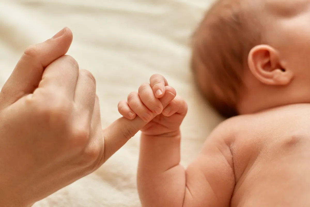 Mão do bebê segurando o dedo da mãe